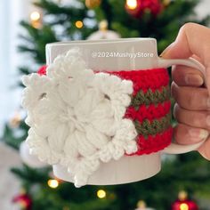 a hand holding a coffee cup with a crocheted santa clause on it