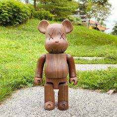 a wooden bear sitting on top of a gravel road