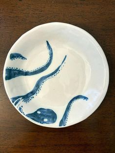 a bowl with an octopus design on the side sitting on top of a wooden table