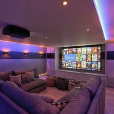 a purple couch sitting in front of a flat screen tv mounted to the side of a wall