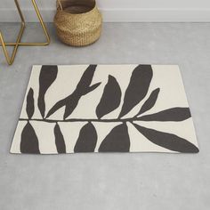 a rug with black and white leaves on it next to a plant potted in a corner