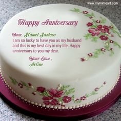 a white cake with pink flowers on it sitting on top of a purple tablecloth