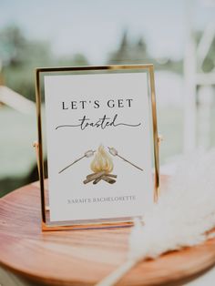 a menu card sitting on top of a wooden table next to a white and gold feather