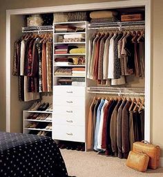 an organized closet is shown with clothes and suitcases on the floor, along with a bed