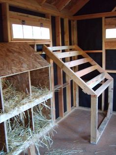 the inside of a barn with hay bales on the floor and stairs leading up to the loft