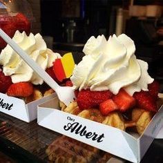 two boxes filled with waffles covered in whipped cream and strawberries next to each other