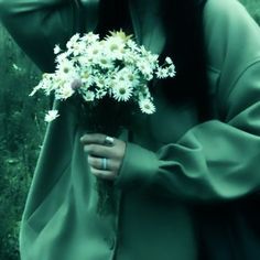 a woman holding a bouquet of white flowers in her right hand and covering her face