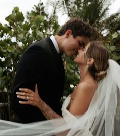 a bride and groom kissing in front of trees