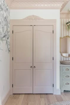 a white closet with two doors and a mirror on the wall next to a dresser