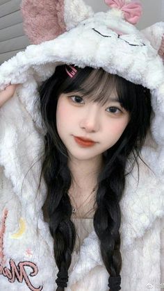 a girl with long black hair wearing a white cat hoodie and pink bow on her head