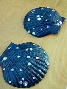 two blue seashells sitting on top of a wooden table next to each other