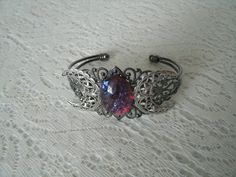 This beautiful sterling silver plated filigree cuff bracelet has a sterling silver plated triple moon design and a large dragons breath fire opal Silver Fantasy Jewelry For Festivals, Mystical Jewelry Bracelet Gift, Mystical Silver Jewelry With Intricate Design, Fantasy Style Silver Bracelet, Silver Gothic Bracelets For Festival, Adjustable Mystical Silver Bracelet, Silver Fantasy Bracelet, Adjustable Silver Fantasy Bracelet, Adjustable Silver Mystical Bracelet