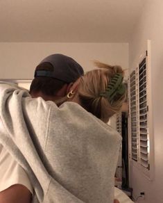 a man and woman wrapped in a blanket looking into an air conditioner