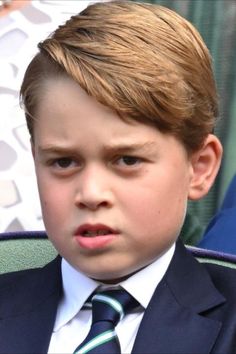 a young boy in a suit and tie looking at the camera with serious expression on his face