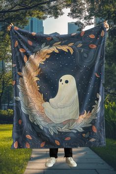 a person holding up a blanket with a ghost on it