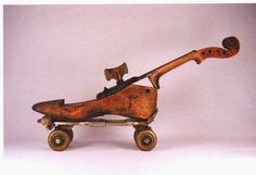 an old wooden toy car with a violin on it's back end and wheels