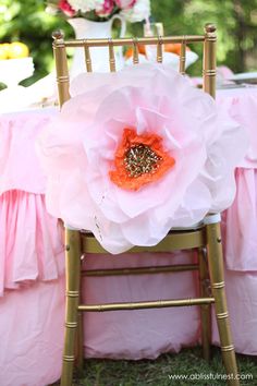 a chair with a flower on the back and pink ruffled table cloths around it