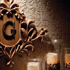 candles are lit in front of an ornate wooden plaque