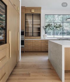 a large kitchen with wooden cabinets and an island countertop in front of a window