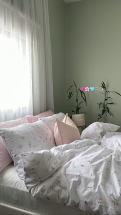 an unmade bed with white sheets and pink pillows in front of a large window