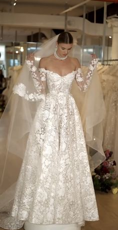 a woman in a white wedding dress with long sleeves