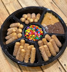 a black tray filled with different types of desserts on top of a wooden table