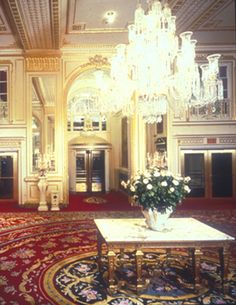 an ornate room with chandelier and red carpeted area in front of it