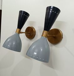 two gray and gold wall lights on a white wall