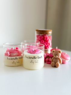 three candles are sitting on a table next to some pink candies and a teddy bear