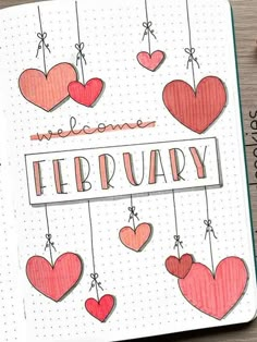 an open notebook with hearts hanging from strings and the words welcome february written on it