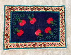 an embroidered placemat with cherries on it