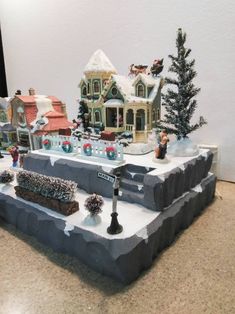 a christmas village is on display in the middle of a room with white walls and brown flooring