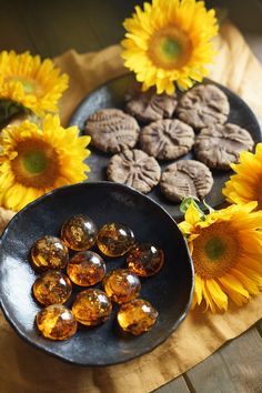 sunflowers and cookies are arranged on a wooden table with two black plates filled with them