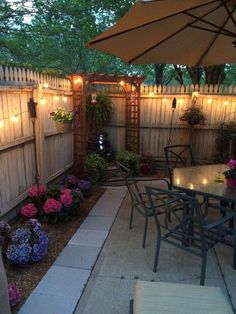 an outdoor dining area with table, chairs and umbrella in the middle of the yard