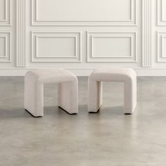 two stools sitting in front of a white wall