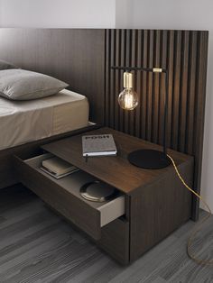 a bedroom with a bed, night stand and lamp on the nightstand next to it