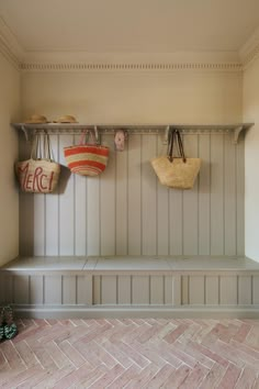 two baskets are hanging on the wall above a bench in a room with wood paneling