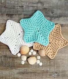 three knitted hats and seashells laid out on a wooden surface with shells