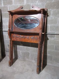 an old wooden table with a mirror on it's top and legs, in front of a brick wall