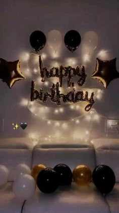 a birthday cake with balloons and lights in the shape of a smiley face on a white couch