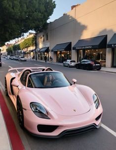 a pink sports car is parked on the side of the road in front of shops