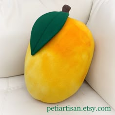 an orange stuffed animal with a green leaf on it's head sitting on a white couch