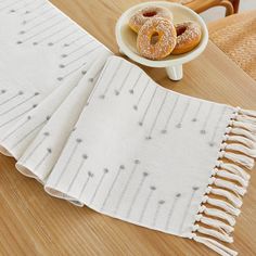 two donuts are sitting on a table next to a white towel and bowl of doughnuts