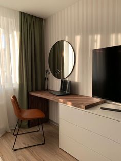 a flat screen tv sitting on top of a wooden table in a living room next to a window