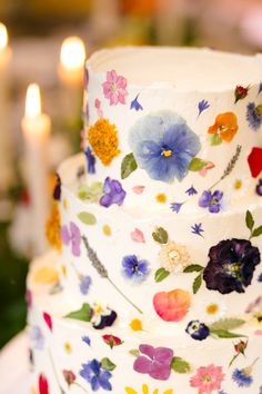 a multi layer cake decorated with flowers and candles