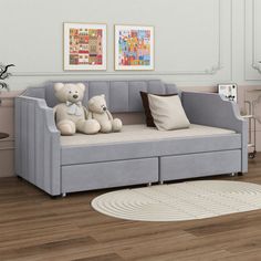 two teddy bears sitting on top of a couch in a room with hardwood floors and white walls