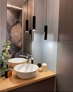 two white bowls sitting on top of a wooden counter next to a wall mounted mirror