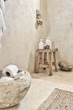 a bathroom with a stool, toilet paper and other items on the table in front of it