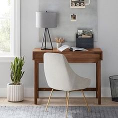 a desk with a lamp, chair and pictures on the wall above it in a living room