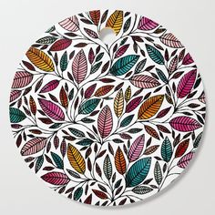 a round cutting board with colorful leaves on it